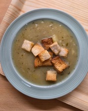 Bowl of soup with crutons in it on a moulded plywood tray