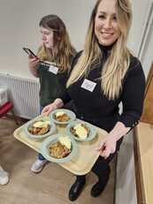 Smiling volunteer holds a tray of deserts